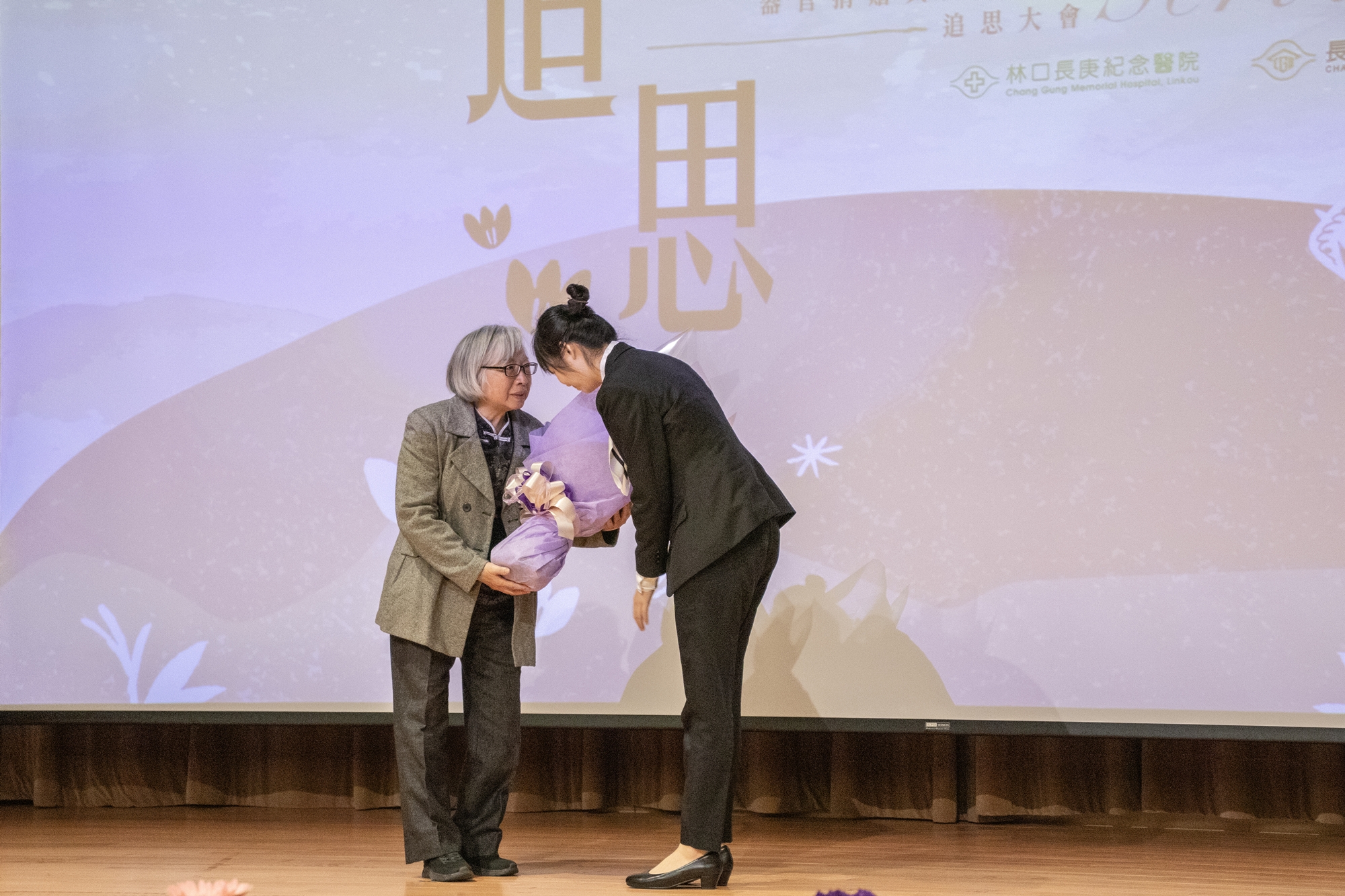 詹佳穎同學(圖右)代表醫學院受教學生獻花給顏雲成大體老師家屬林淑貞女士(圖左)。